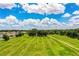 Expansive green field with lush trees and a dirt path leading to the house at 10 Webb Rd, Winter Haven, FL 33881