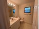 Bright bathroom features a single sink vanity, tiled floors, and a window at 1011 Tequesta Trl, Lake Wales, FL 33898