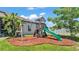 Backyard playground with a swing set, slide, and playhouse on a mulch bed at 1028 15Th Ne St, Winter Haven, FL 33881