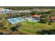 Aerial of community clubhouse, pool, and tennis courts with nearby shopping centers at 104 Morning Glory Cir, Winter Haven, FL 33884