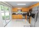 Bright kitchen with stainless steel appliances, wooden cabinets, and sliding glass door to backyard at 114 Ed Padgett Rd, Lakeland, FL 33809