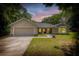 Charming single-story home featuring an attached garage, stone accents, a manicured lawn, and lush surroundings at 13 Count Fleet Dr, Ocala, FL 34482