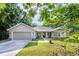 Charming single-story home featuring an attached garage, stone accents, a manicured lawn, and lush surroundings at 13 Count Fleet Dr, Ocala, FL 34482
