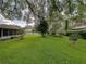 Lush backyard with mature trees, manicured lawn, and landscaping at 1308 Timberidge N Loop, Lakeland, FL 33809
