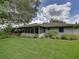 Large backyard featuring a lush green lawn, mature trees, and a screened-in patio at 1308 Timberidge N Loop, Lakeland, FL 33809
