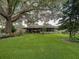 Expansive backyard featuring a covered patio, lush lawn, and mature trees offering shade and tranquility at 1308 Timberidge N Loop, Lakeland, FL 33809