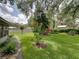 Lush backyard featuring mature trees, flowering shrubs, and a vibrant green lawn, creating a serene outdoor escape at 1308 Timberidge N Loop, Lakeland, FL 33809