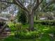Manicured backyard featuring mature trees, lush green grass, plants and a quaint bench at 1308 Timberidge N Loop, Lakeland, FL 33809