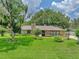 Charming stone home with a well-manicured front lawn and mature trees under a beautiful sky at 1308 Timberidge N Loop, Lakeland, FL 33809