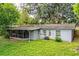 Spacious backyard with a screened porch, mature trees, a wooden fence, and a lush lawn at 1604 Park Dr, Lakeland, FL 33803