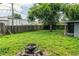 Spacious backyard with lush lawn, mature trees, a perimeter wooden fence, and a fire pit area at 1604 Park Dr, Lakeland, FL 33803