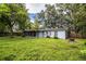 Spacious backyard with lush lawn, a screened in porch, mature trees, and a wooden perimeter fence at 1604 Park Dr, Lakeland, FL 33803