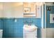 Charming bathroom featuring blue tiled walls, a pedestal sink, and a shower and mirrored medicine cabinet at 1604 Park Dr, Lakeland, FL 33803