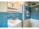 Cozy bathroom featuring blue tiled walls, a sink, and shower with updated fixtures, and a mirrored medicine cabinet at 1604 Park Dr, Lakeland, FL 33803