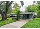 Charming single-story home with gray and black accent colors, a side carport, and lush lawn with mature trees at 1604 Park Dr, Lakeland, FL 33803