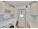 Bright laundry room featuring a washer, dryer, storage cabinets, and door to outside at 1811 Sherwood Hill Dr, Lakeland, FL 33810