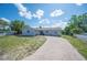 Inviting single-story home with a long driveway, complemented by a white picket fence and mature trees at 1948 Oakland Park Dr, Lake Wales, FL 33898