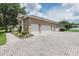 Spacious paver driveway leading to a three-car garage with a stone and stucco exterior at 2026 Indian Sky Cir, Lakeland, FL 33813
