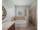 Bright bathroom featuring a tub and separate glass-enclosed shower with neutral tile surround at 2544 Ladoga Dr, Lakeland, FL 33805