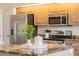 Bright kitchen boasts stainless steel appliances, wooden cabinetry, and a granite countertop with decorative plant and accessories at 2714 Highlands Vue Pkwy, Lakeland, FL 33813