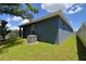 Lawn surrounds the neutral colored house with a fenced backyard, air conditioning and green trees at 312 Walnut Ln, Auburndale, FL 33823