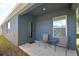 Neutral colored siding with a door and window highlight the covered patio and seating at 312 Walnut Ln, Auburndale, FL 33823