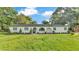 Charming single-story home featuring a white facade, arched entryway, and lush green lawn with mature trees at 3235 Sandpiper Ln, Mulberry, FL 33860