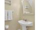 Cozy powder room with a pedestal sink, decorative mirror, and fresh white towels at 4309 Shipp Ct, Lakeland, FL 33813