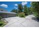 Long cracked driveway leading to a gray garage with lush plants surrounding it, and green grass at 4908 S Bedford Ln, Lakeland, FL 33813