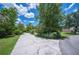 A view of the cracked concrete driveway and a vibrant green lawn, framed by lush trees and colorful bushes at 4908 S Bedford Ln, Lakeland, FL 33813