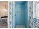 Bathroom featuring blue tiling, unique wallpaper, and an updated shower at 4908 S Bedford Ln, Lakeland, FL 33813