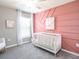 Cozy Bedroom featuring a white crib, soft carpet, and a charming accent wall at 5401 Se 128Th Ln, Belleview, FL 34420