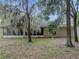 Backyard with mature trees, some covered in Spanish moss, and a screened in porch at 5522 1St Se St, Lakeland, FL 33812