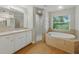 Bathroom featuring a soaking tub, glass shower and a white vanity at 5522 1St Se St, Lakeland, FL 33812
