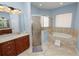 Bright bathroom showcasing a glass shower, soaking tub, vanity, large mirror, and tile flooring at 6217 Ashley Dr, Lakeland, FL 33813