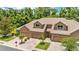 View of a home with a three-car garage, a brick driveway, manicured landscaping, and a lush backdrop at 6365 Torrington Cir, Lakeland, FL 33811