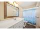 Bathroom features vanity with white countertop, large mirror, and shower with a blue patterned curtain at 6507 Shadowbrook Run, Lakeland, FL 33813