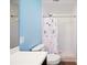Bright bathroom with white tiled shower and floral shower curtain plus blue accent wall at 6507 Shadowbrook Run, Lakeland, FL 33813
