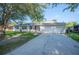 Charming single-story home with white brick exterior, lush tree, and a driveway at 6507 Shadowbrook Run, Lakeland, FL 33813