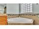 Bright bathroom featuring a large soaking tub with tile surround and a window with glass blocks at 6757 High Grove Dr, Lakeland, FL 33813