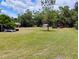 Expansive backyard with lush green grass, mature trees, and multiple outbuildings for ample storage at 6915 Dove Meadow Trl, Lakeland, FL 33810