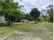 Expansive backyard showcasing mature trees, green grass, and rustic outbuildings with a vehicle in the distance at 6915 Dove Meadow Trl, Lakeland, FL 33810