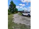 White SUV parked on a long dirt driveway bordered by trees, leading towards other vehicles in the distance at 6915 Dove Meadow Trl, Lakeland, FL 33810