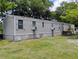 Tan single-story home with traditional shutters and a satellite dish, surrounded by lush trees at 6915 Dove Meadow Trl, Lakeland, FL 33810