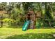 A backyard wooden playset with swings and slide for children in a lush green setting at 6920 Newman E Cir, Lakeland, FL 33811
