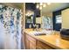 Bathroom with oak vanity, blue accent wall and shower with floral-themed curtain at 6920 Newman E Cir, Lakeland, FL 33811