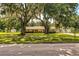 Ranch-style house with mature trees in front and a well-maintained lawn, giving it a classic look at 6920 Newman E Cir, Lakeland, FL 33811