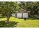 Detached two-car garage with white doors sits on a large lot with mature trees in the background at 6920 Newman E Cir, Lakeland, FL 33811