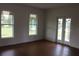 Bright living room with hardwood floors, complemented by natural light from two large windows and glass patio doors at 701 1St Ne St, Fort Meade, FL 33841