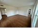 Large living room with sleek wood floors, freshly painted white walls, and abundant natural light from large windows at 701 1St Ne St, Fort Meade, FL 33841